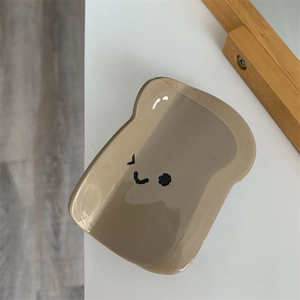 Dettaglio della molletta grigia a forma di toast con faccina sorridente in acetato