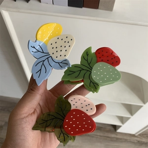 Détail de trois pinces à cheveux en forme de fraise en acétate aux couleurs vives et variées