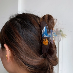 Detail showing acetate hair claw clip with blue whale design worn by a female model