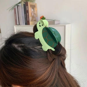 Detail of green turtle cellulose acetate hair claw clip styled on long brown hair