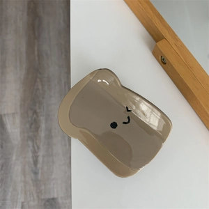 Dettaglio di un fermaglio per capelli a forma di toast marrone con un viso sorridente