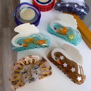 Creative acetate hair claws featuring swan, sun, and star designs with marble textures