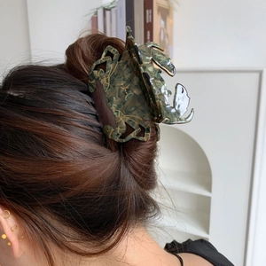 Détail d'une pince à cheveux crabe créative avec texture de marbre vert sur chignon