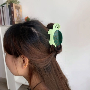 Detailed view of turtle-shaped acetate hair claw clip worn on hair with green finish