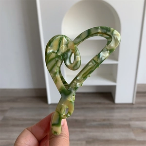 Detailed close-up of large acetate heart hair claw with green marble texture finish