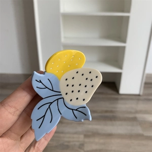 Gros plan détaillé d'une pince à cheveux fraise en acétate avec design de feuille colorée