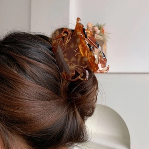 Détail d'une pince à cheveux crabe à motif écaille de tortue ambrée avec traits dorés