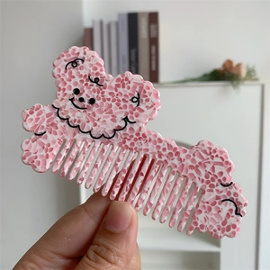 Close-up of a pink floral acetate hair comb with a cute cartoon dog face design