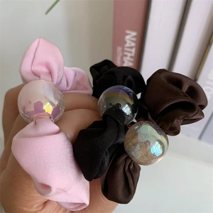 Close-up of satin hair scrunchies with iridescent laser spheres in pink, black and brown