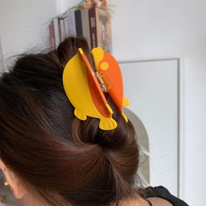 Pince à cheveux poisson orange et jaune vibrante portée pour un look doux et sucré