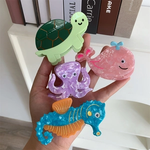 Macro detail of four colorful sea animal acetate hair claws in turtle and whale shapes