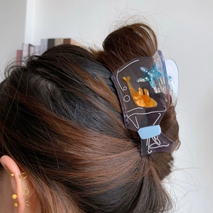 Close-up of a lilac ocean-themed hair claw with sea star and fish on a bun hairstyle