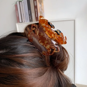 Détail d'une grande pince à cheveux crabe ambrée portée dans un chignon décontracté