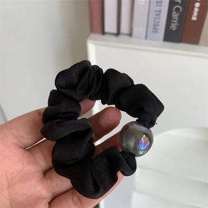 Detail of black fabric scrunchie with a large iridescent iridescent bead decoration