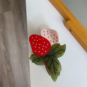 Détail de la pince à cheveux fraise en acétate rouge et rose avec texture de feuille