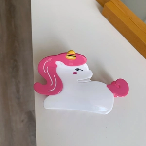 Close-up of cute unicorn hair claw clip in white and pink acetate material with yellow horn