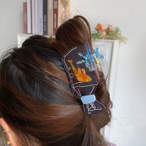 Detail view of transparent purple acetate hair claw clip with sea star and fish on hair