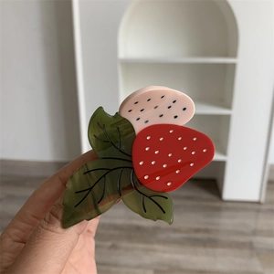 Vue détaillée d'une pince à cheveux fraise en acétate aux couleurs rouge et vert vif