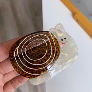 Détail d'une pince à cheveux en forme d'escargot avec motif léopard et finition nacrée