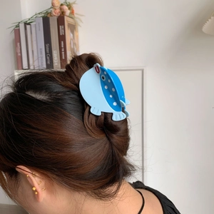 Pince à cheveux en forme de poisson bleu en acétate sur une chevelure bouclée