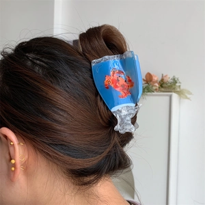 Detailed view of the blue translucent acetate hair claw featuring an orange crab design