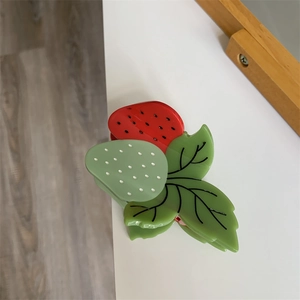Vue détaillée de la pince à cheveux fraise en acétate brillant avec feuilles colorées