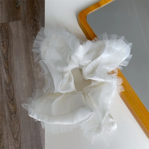 Detail of white satin lace scrunchie with elegant ruffled edges and mesh texture