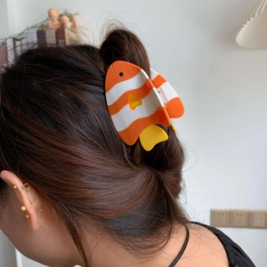 Détail d'une pince à cheveux en forme de poisson-clown portée sur une demi-queue