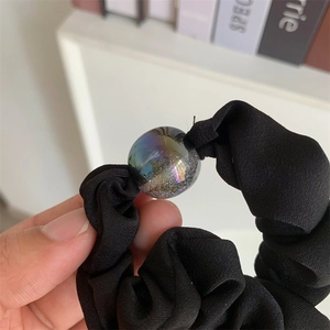 Detail of black chiffon scrunchie featuring a shimmering aurora bead and soft texture