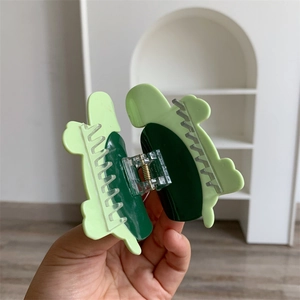 Detail of dual-tone green acetate hair claw clip showing secure metal spring and teeth