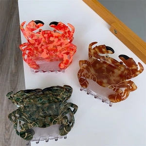 Vue détaillée de pinces à cheveux crabe en acétate marbré orange, marron et vert foncé