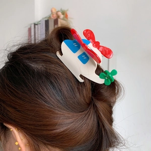 Détail d'une pince à cheveux en acétate en forme d'hélicoptère sur une queue de cheval