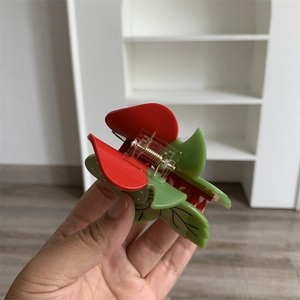 Détail de la pince à cheveux fraise montrant le matériau acétate et le ressort