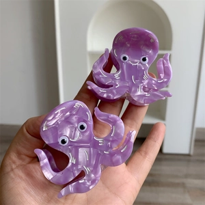 Detailed view of two purple marble acetate octopus hair claws with cute cartoon facial details