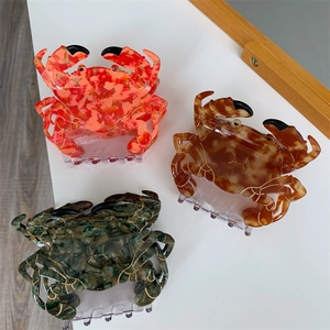 Vue détaillée de grandes pinces à cheveux crabe en marbre rouge, ambre et vert
