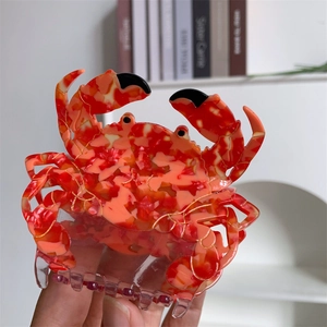 Vue détaillée d'une grande pince à cheveux crabe avec motifs en acétate marbré rouge et orange