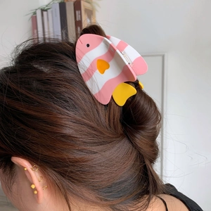 Détail d'une pince à cheveux poisson fugu rose avec motif de cœur jaune sur les cheveux