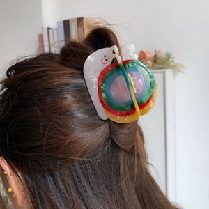 Détail d'une pince à cheveux colorée en forme d'escargot en acétate sur cheveux
