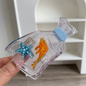 Detail of creative bottle-shaped hair claw featuring blue starfish and orange fish inside