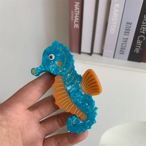 Detailed view of seahorse-shaped hair claw clip in blue acetate with orange fin accents