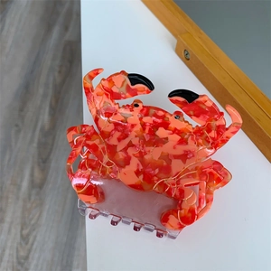 Détail d'une pince à cheveux en forme de crabe avec texture marbrée orange et dents claires