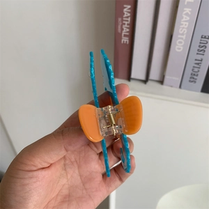 Detail of blue and orange octopus acetate hair claw with durable golden metal spring