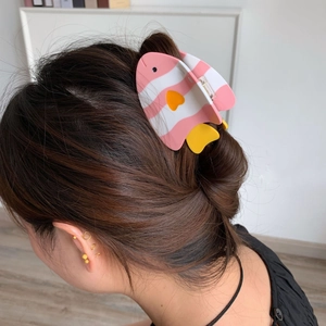 Détail de la pince à cheveux en forme de poisson en acétate sur un chignon