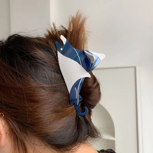 Stingray hair claw clip with blue and white acetate design on brown braided hair