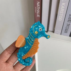 Macro shot of a seahorse-shaped hair claw clip with blue marble acetate texture
