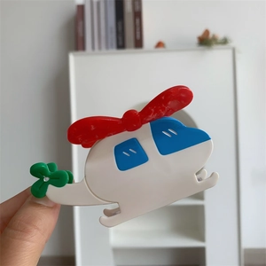 Détail d'une pince à cheveux hélicoptère en acétate coloré tenue à la main avec soin