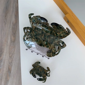 Détail de la texture marbrée et dorée sur les pinces à cheveux crabe sur fond blanc