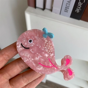 Detail of a pink acetate hair claw clip in whale shape with blue bow and white dots