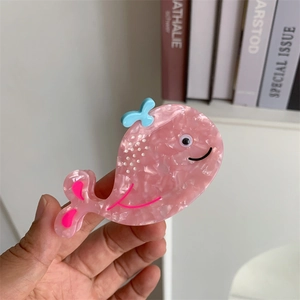 Detail of whale-shaped hair claw clip in pink floral acetate with blue spray accents