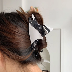 Detailed view of stingray-shaped acetate hair claw clip worn on long hair for styling